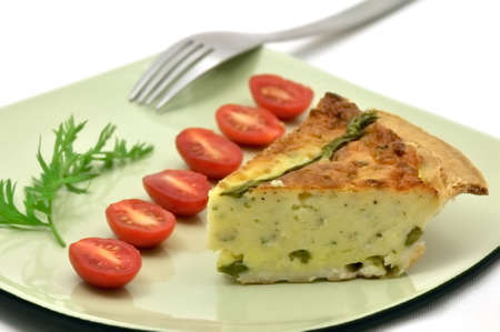 Asparagus quiche slice on a green plate with tomatoesの写真素材