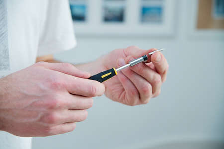 Man holds a screwdriver in his hands - white skin, black and yellow screwdriver