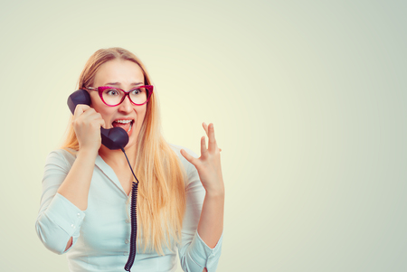 Young screaming woman in glasses speaking on telephones looking away in fearの写真素材