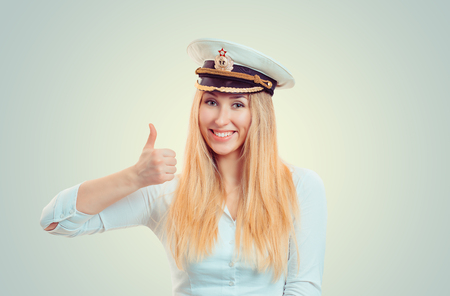Happy blond woman wearing white shirt and navy service cap showing thumb up and smilingの写真素材