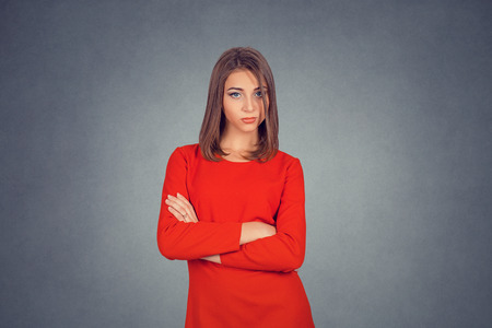 Portrait of serious confident woman standing with arms folded looking at you camera. Business lady in red dress, bob hairstyle. Isolated on gray grey studio wall Background. Negative face expression.の写真素材
