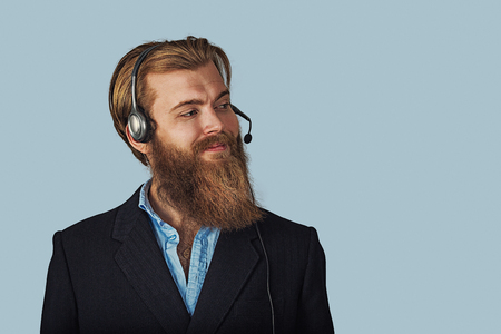 Bearded hipster businessman. Friendly customer service guy over light blue with clipping path Positive face expression, human emotion, body language, reaction, attitude. Studio horizontal shot.の写真素材
