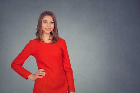 Portrait of young attractive woman smiling. Business woman in red dress, bob hairstyle. Isolated on gray grey studio wall Background. Positive face expression, human emotion, body language, reaction.の写真素材