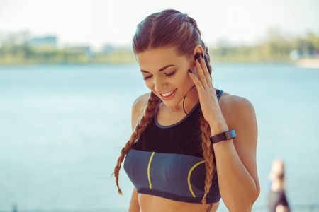 Charming brunette in sportive top listening to music with headphones on streetの写真素材