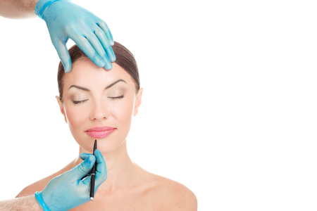 Facial lips cosmetic plastic surgery. Doctor hands holding face about to draw lines with marker on lips isolated on white background with copy space. Beautify conceptの写真素材