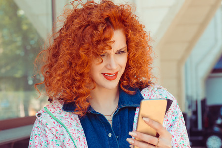 Portrait of young sad annoyed woman, receiving bad sms isolated on city building backgroundの写真素材