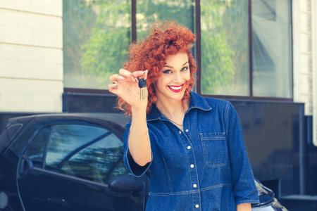 Portrait happy, smiling, young attractive woman, buyer near her new car showing giving keys isolated outside dealer dealership lot office. Personal transportation auto purchase conceptの写真素材