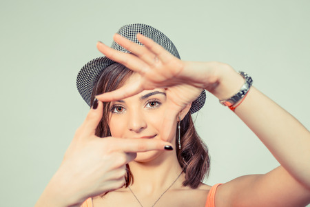 Happy hipster girl bob hair style woman with gray hat making frame with fingers isolated on a light green yellow background.の写真素材