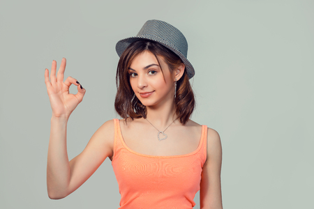 Excited happy young optimistic woman teenage girl giving ok sign gesture with one hand isolated on light green gray wall background. Positive human emotions face expression body languageの写真素材