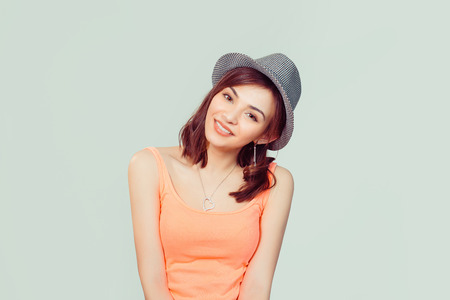 Cute hipster girl laughing, woman in gray hat and pink shirt smiling looking at you camera isolated on light green studio wall background. Positive human emotions, face expression, reaction, attitude.の写真素材