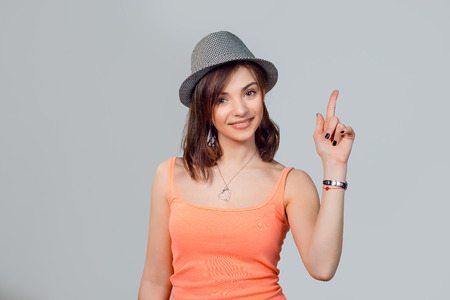 Pointing up. Closeup portrait intelligent cute young woman finger up showing the copy space, isolated gray background. Positive emotion facial expression feeling, attitude, perceptionの写真素材