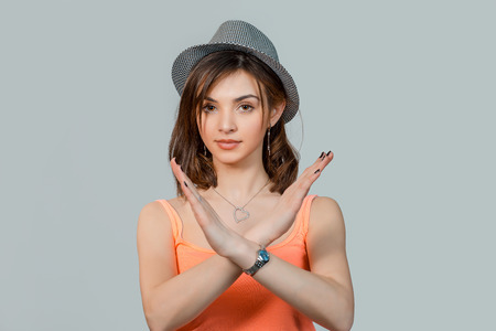 Angry pissed of woman in gray hat showing stop, no, hands gesture isolated on light gray backgroundの写真素材