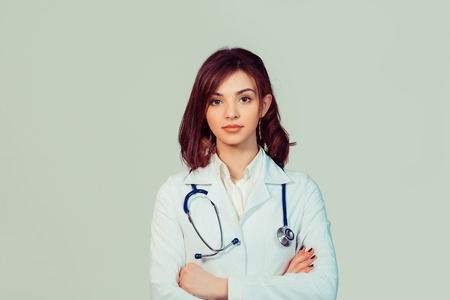 Woman in white doctor robe with stethoscope arms crossed isolated on light green backgroundの写真素材