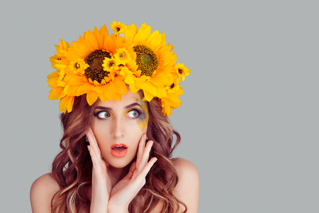 Wow. Close up portrait young woman beautiful girl with floral crown fron sunflowers looking excited holding her mouth opened, hands on cheeks, isolated grey wall. Shocked surprised stunned. Reactionの写真素材