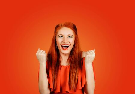 Happy successful student, euphoric woman winning, fist pumped, celebrating success isolated on Red backgroundの写真素材