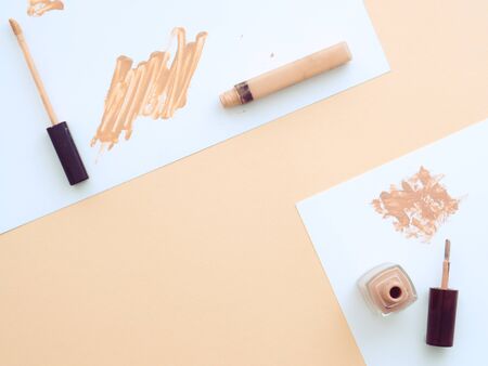 Beige concealer, nail polish and black eyebrow gel on two sheets papers isolated on nude skin rose pink color background. Flat lay, top view copy space. Cosmetics for Natural makeupの写真素材