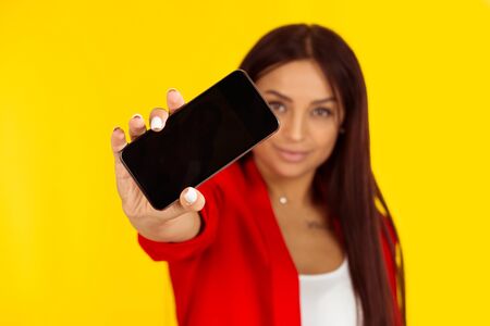 Close up portrait of a happy smiling woman holding smart phone with a blank black screen. Focus on...