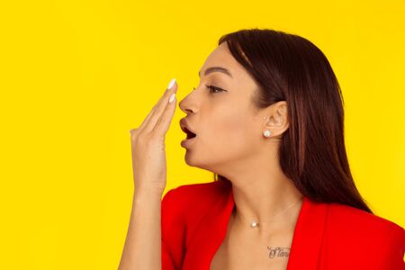 Woman checking her breath, gum odor with her hand. Mixed race model isolated on yellow background with copy space. Horizontal image. Natural, no makeup.の写真素材