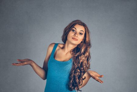 Tell me What to do, where to go? Confused brunette girl business woman pointing with hands in two different directions looking at camera. Mixed race model isolated on gray background with copy spaceの写真素材