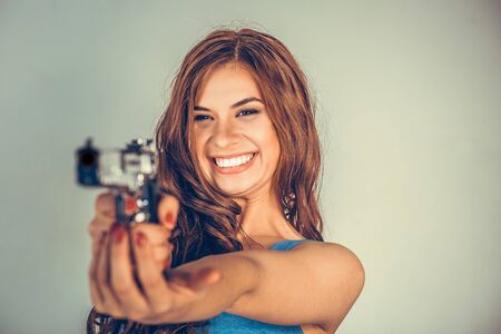 Beautiful young woman with a gun. Brunette holding Handgun looking, aimed, pointing at...