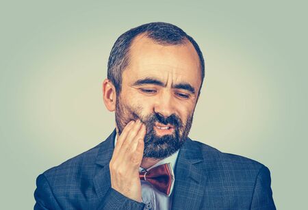 Closeup portrait mature man with sensitive toothache crown problem about to cry from pain touching...