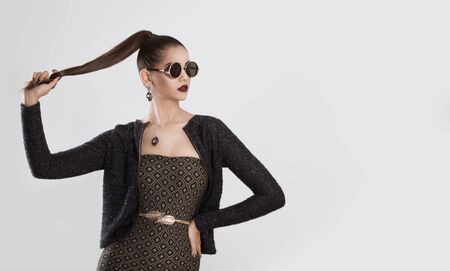Closeup portrait confident successful beautiful attractive young woman fashion girl with sunglasses pulling out her ponytail hair looking serious isolated white grey background Neutral face expressionの写真素材