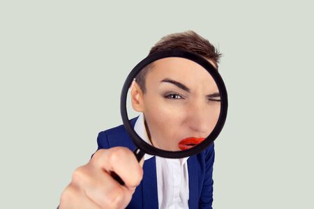 Investigator Disgusted by what she see find out concept. Expressive Woman looking through magnifying lens disgust on her face isolated light green white backgroundの写真素材