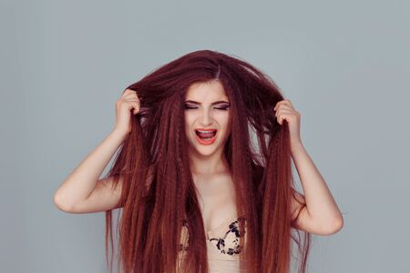 Closeup portrait stressed, frustrated shocked business woman pulling hair out yelling screaming temper tantrum isolated grey wall background. Negative human emotion facial expression reaction attitudeの写真素材