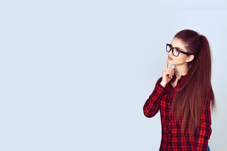 Portrait happy beautiful woman thinking looking up isolated light blue wall background with copy space. Human face expressions, emotions, feelings, body language, perceptionの写真素材