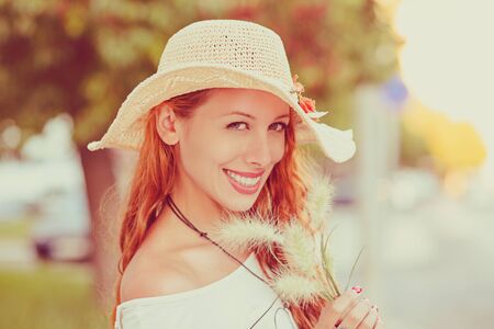 Summer girl portrait. Asian Russian woman in straw hat smiling happy on sunny summer or spring day outside in city near the road. Pretty mixed race Caucasian / Chinese Asian young woman outdoors.の写真素材