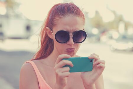 Upsetting message. Portrait of an annoyed and frustrated young woman looking at the phone isolated...