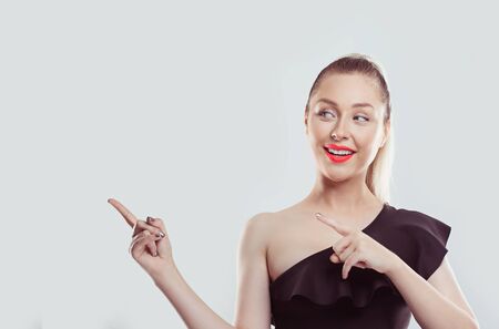 Look right here on my right. Portrait of young beautiful woman pointing fingers up to side at empty copy space Standing happy smiling girl isolated on white background Advertisement of product conceptの写真素材