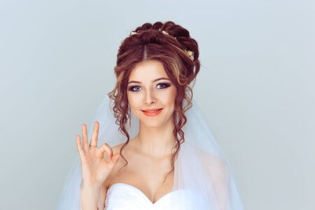 Portrait beautiful happy young woman showing Ok sign with hand isolated on light blue wall background. Positive human emotions face expression body languageの写真素材