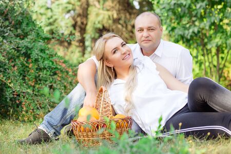 Happy couple outside hugging and posing having picnic isolated outdoors green foliage backgroundの写真素材