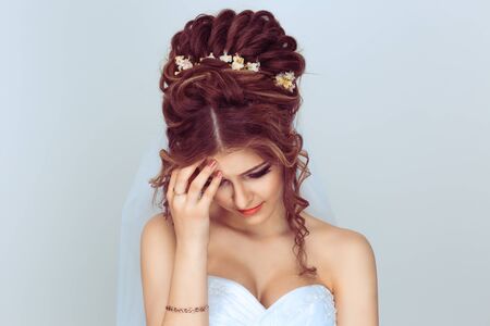 Sad bride looking down sadly having doubts about the wedding isolated on white backgroundの写真素材