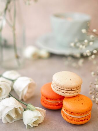 Macaroons cakes and white rose flowers and a Morning cup of coffee on light gray stone table background. Beautiful breakfast. Selective focus. Vertical imageの写真素材