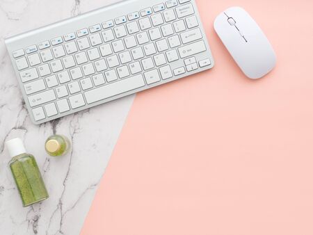 Flat lay, top view of pink table desk frame. Feminine desk workspace with laptop, curative cosmetics, green shower gel and shampoo containers, computer keyboard and mouse isolated on a pink backgroundの写真素材