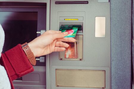 Hand of woman uses credit card to withdraw at Atm Bank terminal. Modern style. ATM cash terminal...