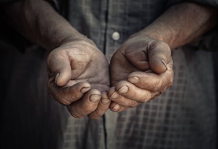 Wrinkled old hands begging asking for money. Closeup portrait senior elderly wrinkled hands isolated dark black background. Human emotions attitude reaction, body language. Charity Concept sign symbolの写真素材