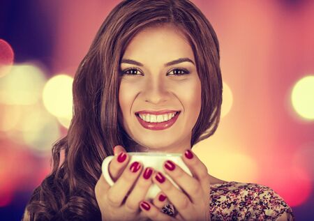 Coffee. Young beautiful Girl woman drinking Tea Cappuccino in trendy cafe shop. Beauty Model with Cup of Hot Beverage. Closeup portrait, warm colors. Human emotions positive facial expressions feelingの写真素材