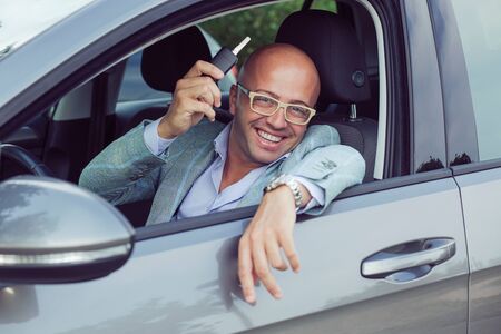 Handsome business man male holding car keys in hand showing his new carの写真素材