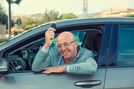 Handsome business man showing keys of his new car. Retro toned photo.