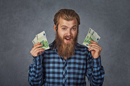 Portrait happy young man with money euro banknotes ecstatic celebrates success screaming isolated on gray background. Financial freedom achievement conceptの写真素材