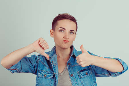 Thumb up or thumb down. Skeptical thinking woman judging deciding how to rate a situation. Is it...