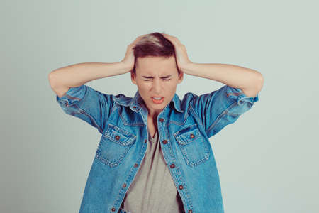 Stressed Pretty brunette getting a headache with hands on head on green grey white background