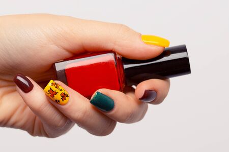 Autumn fall nail art trend. Hand with professional manicure holding nail polish jar bottle.  Closeup...
