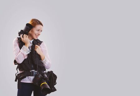 Portrait close up of beautiful young woman photographer girl thinking looking away, up holding camera isolated on gray wall background with copy space. Human face expression emotions feeling body languageの写真素材