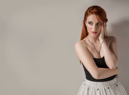 Beauty woman portrait with red hair. Beautiful redhead girl looking to side with hands touching...