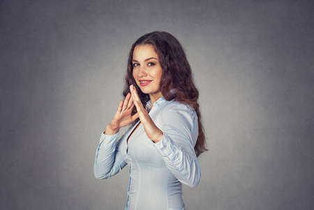 Closeup portrait of humorous, cute cheerful woman with smile on face raising hands in the air with karate chop. Cute smiling female in blue formal shirt Isolated blue studio Background. Positive face expression.の写真素材