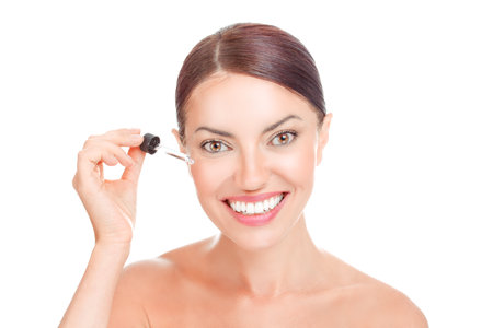 Girl woman applying anti mimic wrinkles eye face serum essential oil smiling isolated on white background. Mixed race latina african american caucasian model. Positive face expressionの写真素材